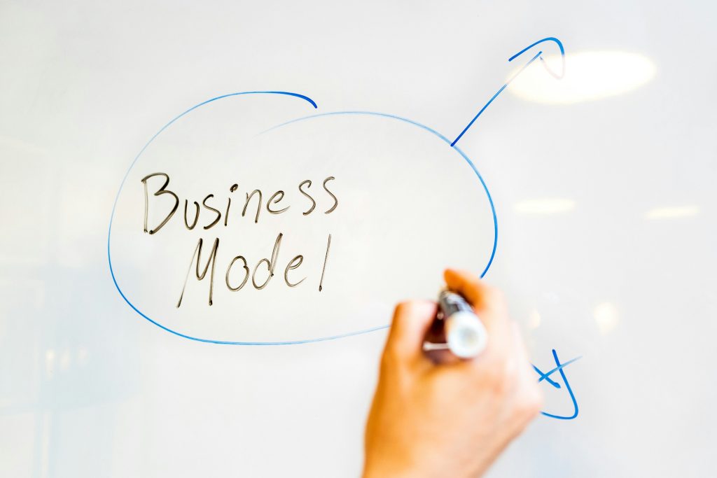 Hand schreibt "Business Model" mit Marker auf Whiteboard – Unternehmensplanung Workshop