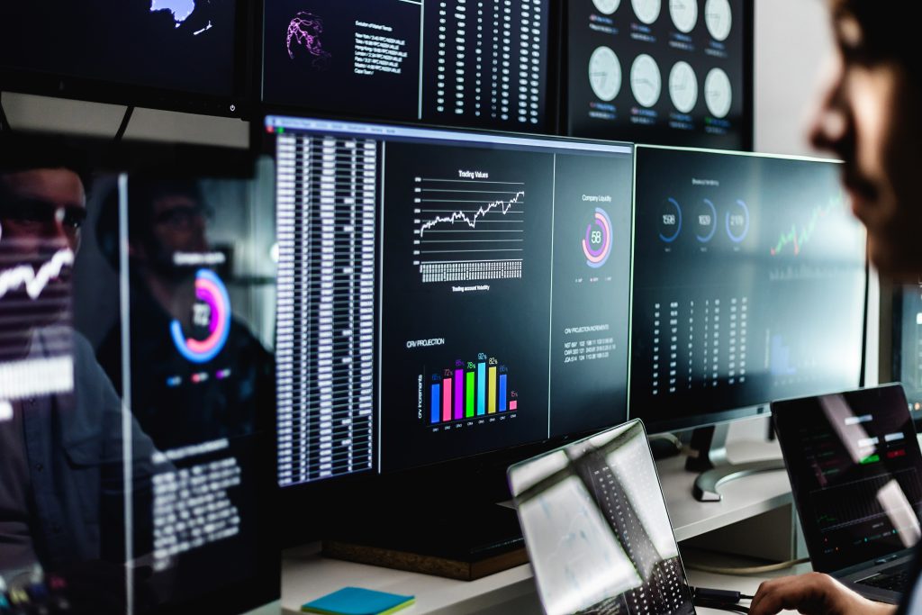 Arbeitsplatz mit mehreren Bildschirmen und detaillierten IT-Dashboards zur Analyse des Systemzustands
