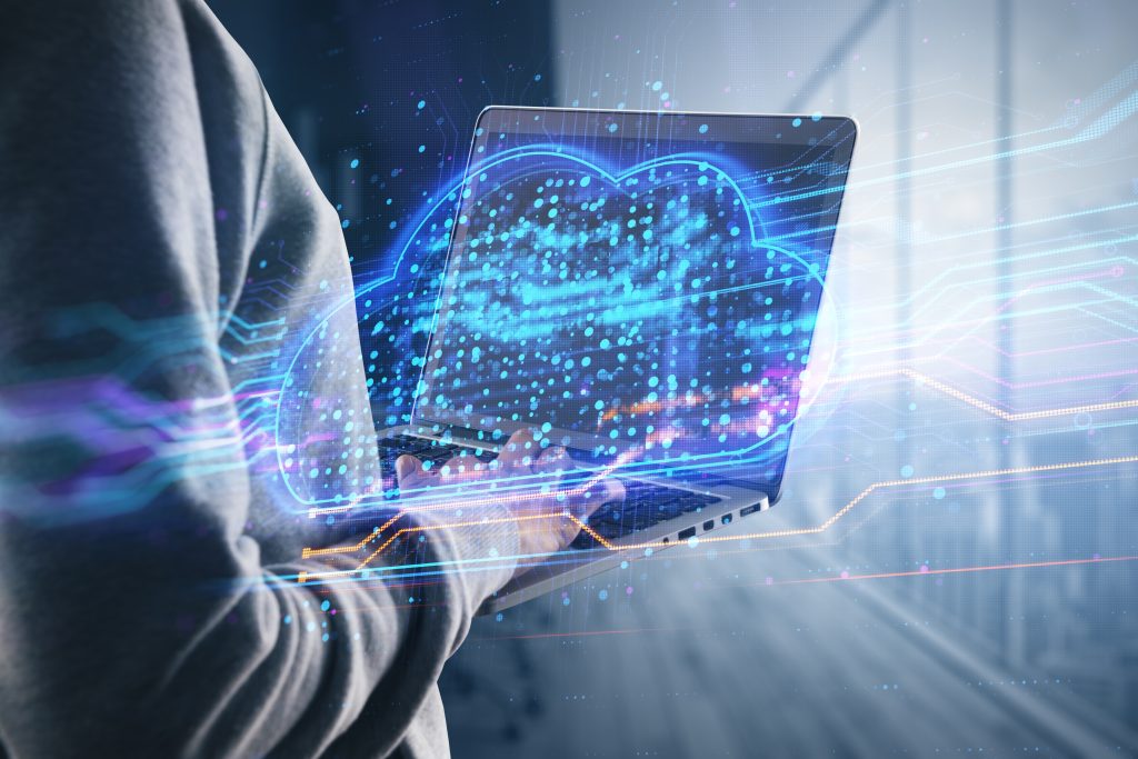 Person bedient einen Laptop mit leuchtendem Cloud-Symbol für moderne IT-Infrastruktur und Datenanalyse