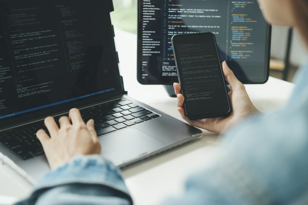 Softwareentwickler programmiert Quellcode auf Laptop und Smartphone