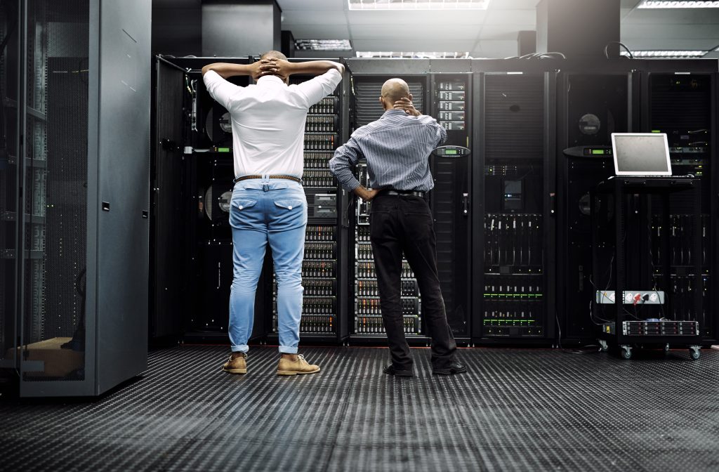 Zwei IT-Experten stehen nachdenklich vor geöffneten Server-Racks in einem Rechenzentrum