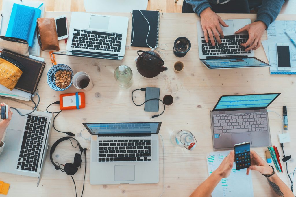 Team arbeitet gemeinsam an mehreren Laptops am Schreibtisch – Zusammenarbeit im digitalen Arbeitsalltag