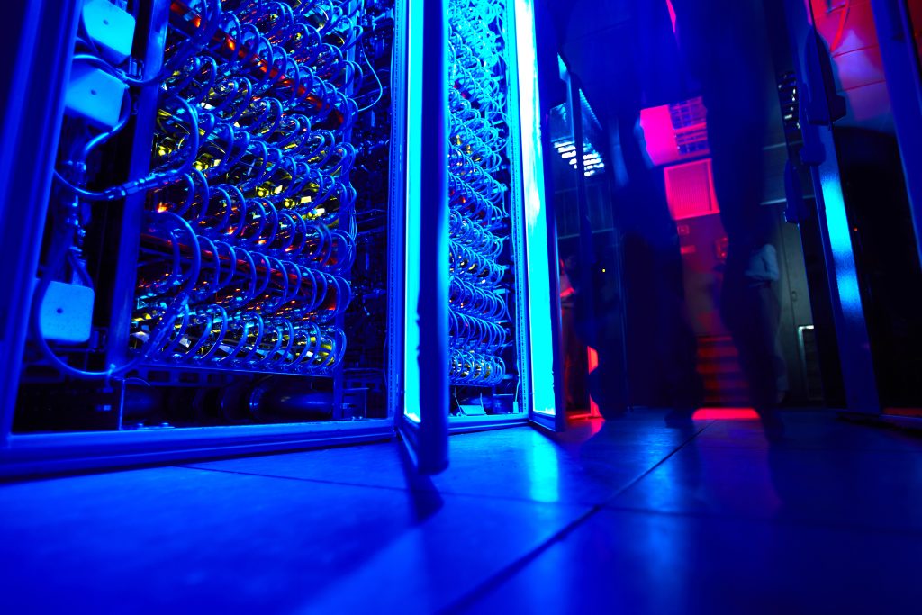 Nahaufnahme eines Serverracks mit Glasfaserkabeln, beleuchtet in Blau und Rot