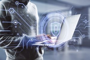 Person mit Kapuzenpullover arbeitet am Laptop mit digitalem Sicherheitsschild-Symbol