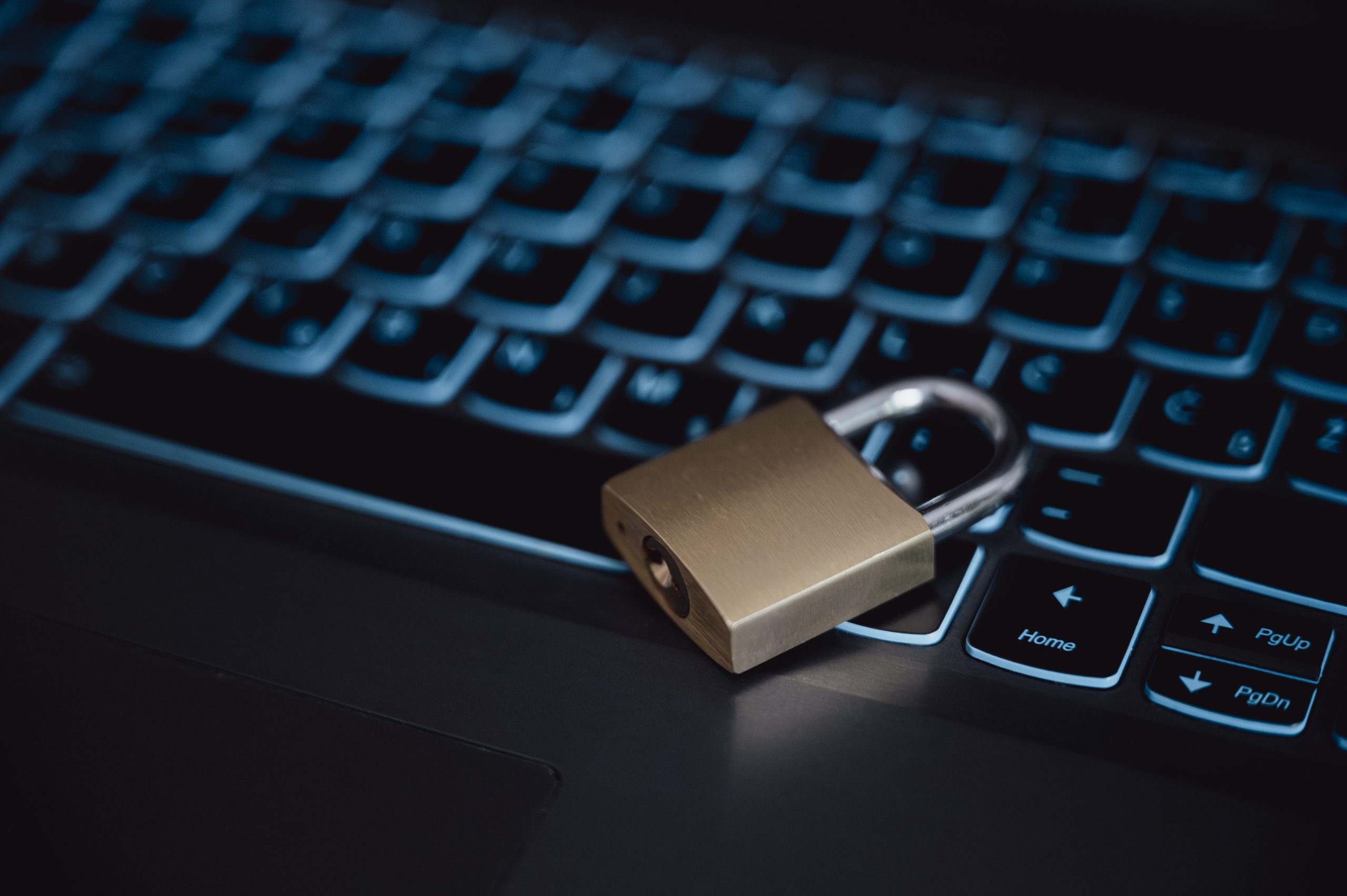 IT Sicherheit symbolisiert durch Vorhängeschloss auf beleuchteter Laptop-Tastatur